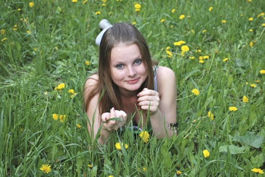 beautiful girl on summer lawn with dandelions