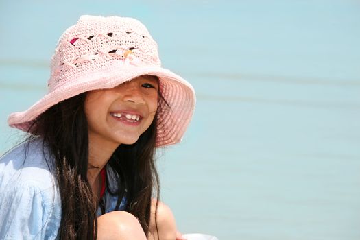 Cute little girl in pink hat at beach