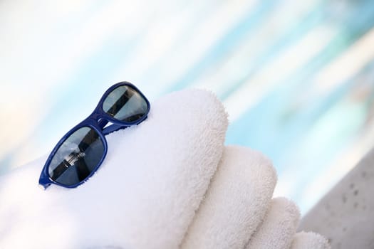 white Towels and blue sunglasses by pool