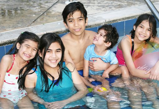 Five happy children sitting in outdoor  pool
