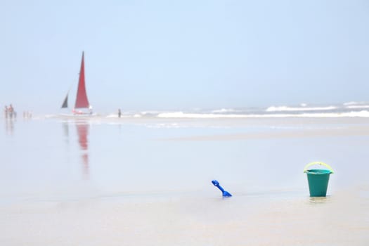 Relaxing Beach scenario with sailboat , bucket and shovel