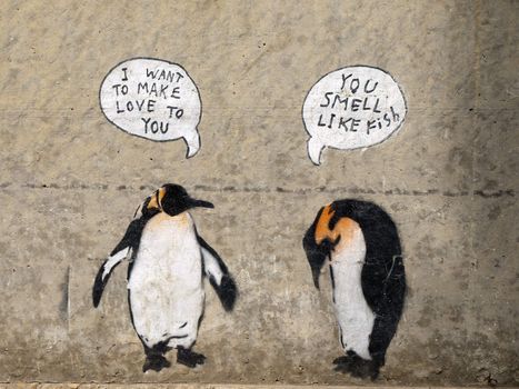 Penguin stenciled graffiti on a cement wall.
