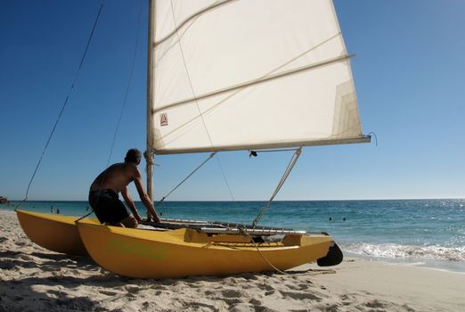 Man with a sail boat on the beach