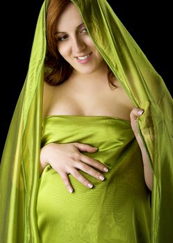 Pregnant woman posing on a black background with beautiful dress