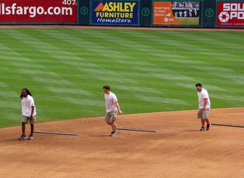 A crew rakes the baseball infield during a break.
