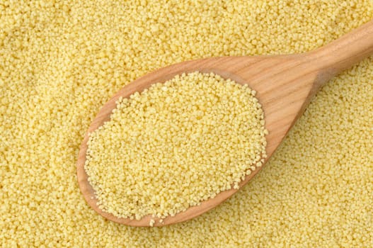 Wheat semolina couscous background with wooden spoon