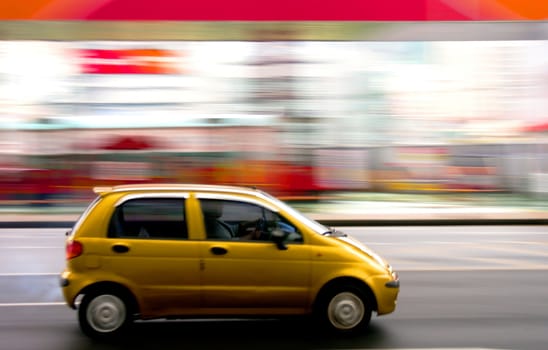 A yellow car speeding through a city center. Motion blur was used for effect.