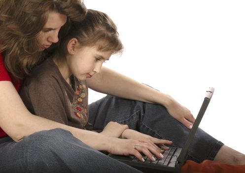 Mother with daughter work at computer sitting on floor.