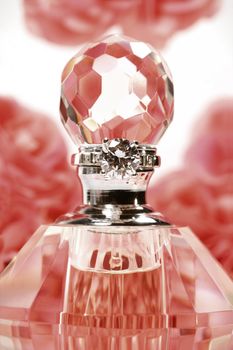Perfume bottle with pink roses in background