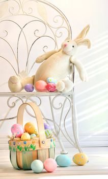 Stuffed rabbit on iron chair with easter basket and eggs