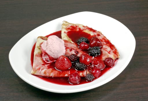 Pancake with icecream and berry in plate on brown wooden table