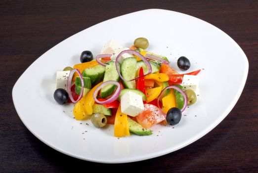 greek salad with vegetables on dark table