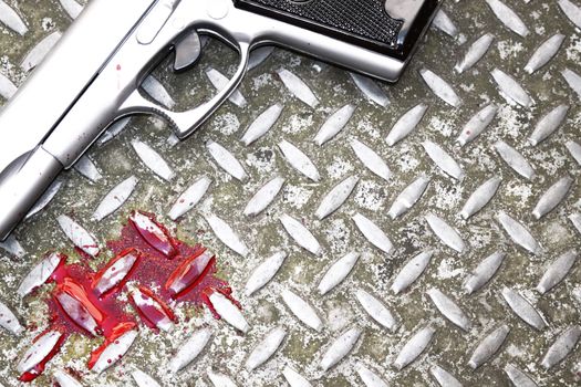 illustrative styled image of blood splatters and a hand gun on a steel drain cover. room for copy etc.