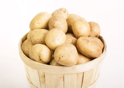Patatoes in a woven basket on a white backround