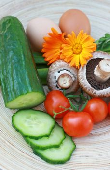 Salad ingredients set on a oval wooden platter.Tomato,mushroom,beans,cucumber and eggs. A wooden platter of organically grown ingredients.