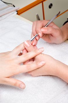 applying manicure - nail cuticle cleaning with special instrument