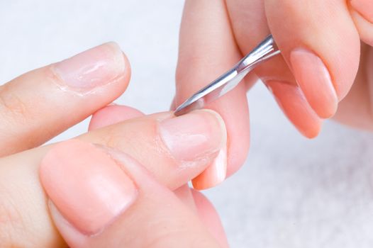 manicure applying - cleaning the cuticles with special istrument