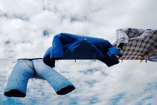 Drying trousers and shirts on wind with copy space over cloudy sky background