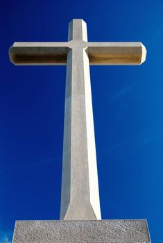 Big Christian stone cross over blue sky and clouds - bottom racurs