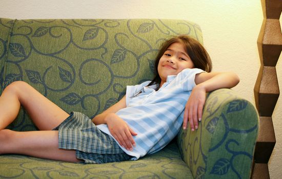 Little girl relaxing on green couch or sofa
