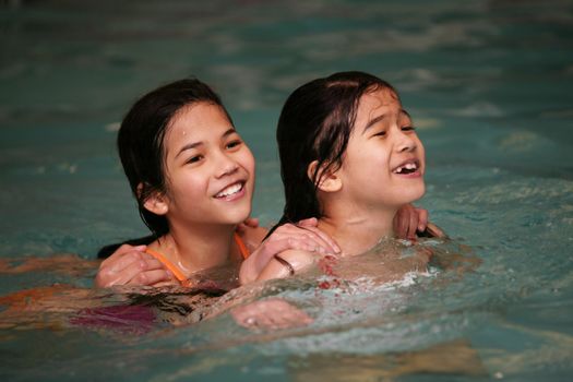 Two girls in swimming pool playing together