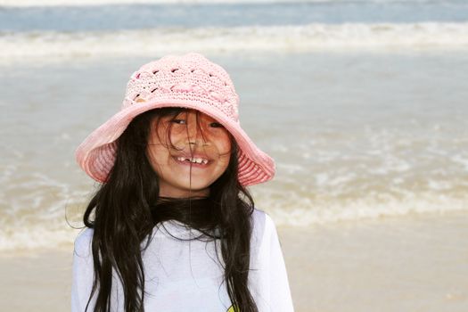 Cute little girl in pink hat at beach