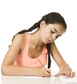 Young girl with plaits writes with concentration 

