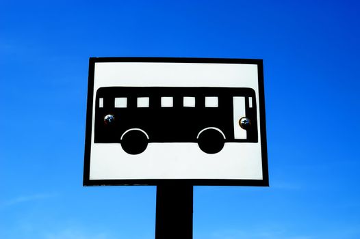 A bus signpost against sunny blue sky.