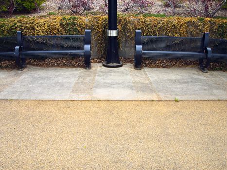 Two new modern benches along a walkway to a park.