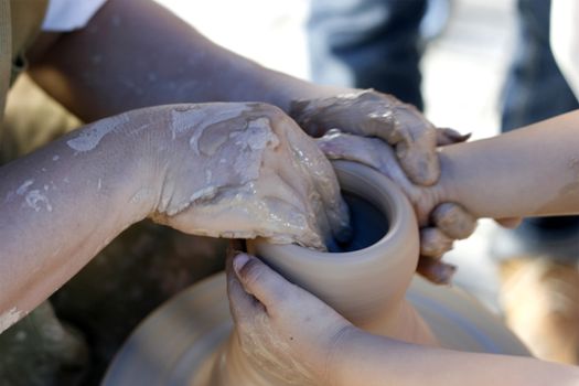 Molding his Future concept - child hand teaches by an adult in pottery making.