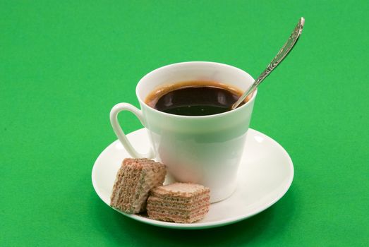 	
a cup of black coffee in the diced wafers on a green background
