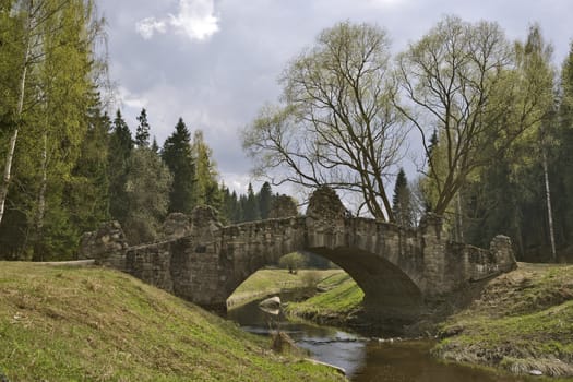 Ancient stone bridge over river in spring park