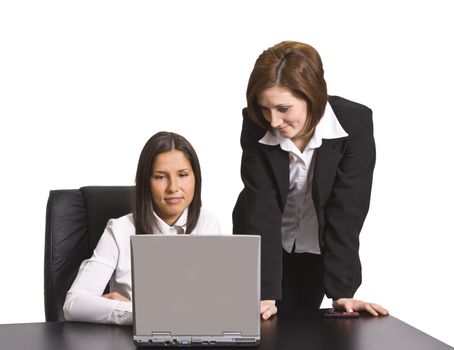 Two young businesswoman working together on a laptop at their office desk.