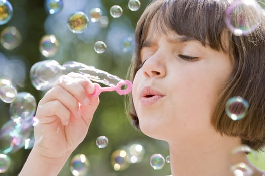 young female child blowing a stream of bubbles into the air