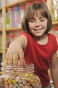 young girl grabbing sweets from a jar in a shop