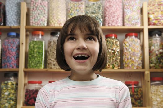 young girl smiling in awe at rows of sweets