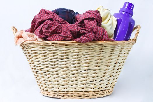 A basket is filled with dirty laundry and detergent.