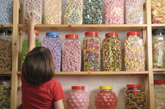 child reaching for sweet jar on top shelf