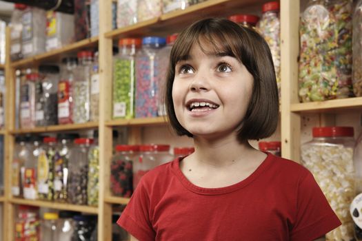 young girl smiling in awe at rows of sweets
