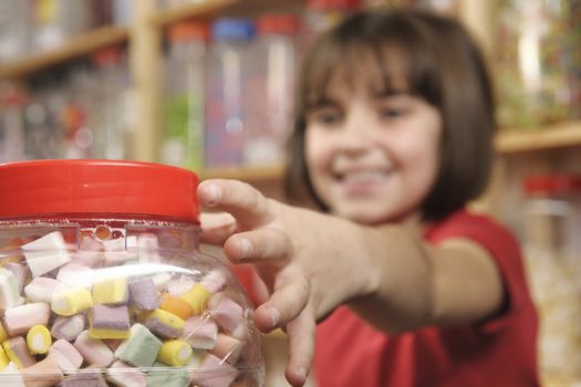 young girl grabbing a jar of sweets in shop