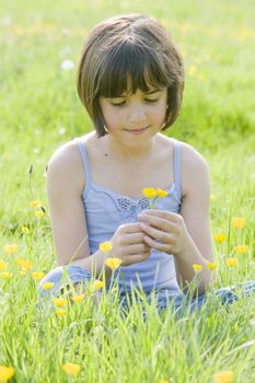 young female child sitting cross legged in a field full of buttercups