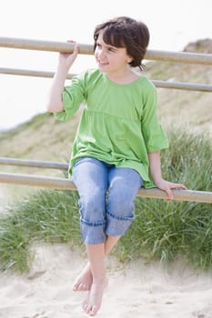 young child sitting on railings by the beach
