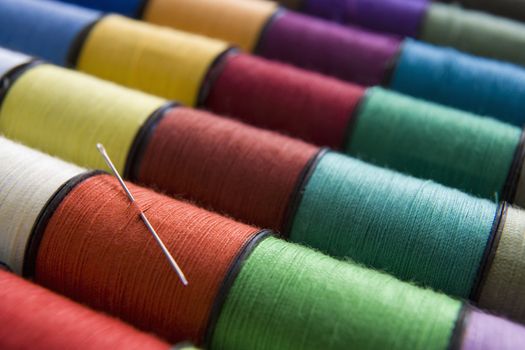 various colours of cotton reelsin a row with a needle