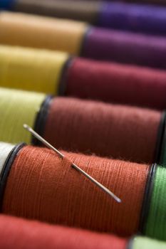 various colours of cotton reelsin a row with a needle