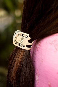 Hair clip with the word love attached to long black hair close up.