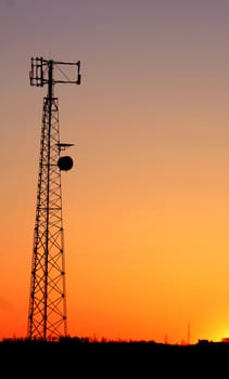 A cell phone tower silhouette in the sunset
