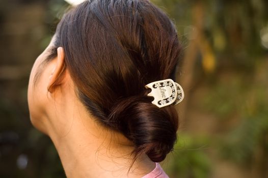 A love hair clip holding a girl's hair twirled up. back view