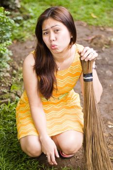Asian girl holding a broom while lips are puckered