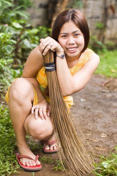 Overqualified maid posing with a broom while sweeping garden