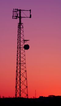 A cell phone tower silhouette in the sunset
